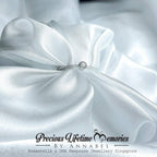 Close-up of white satin fabric with a small jewelry piece on a white background, featuring 'Precious Lifetime Memories by Annabel' branding.