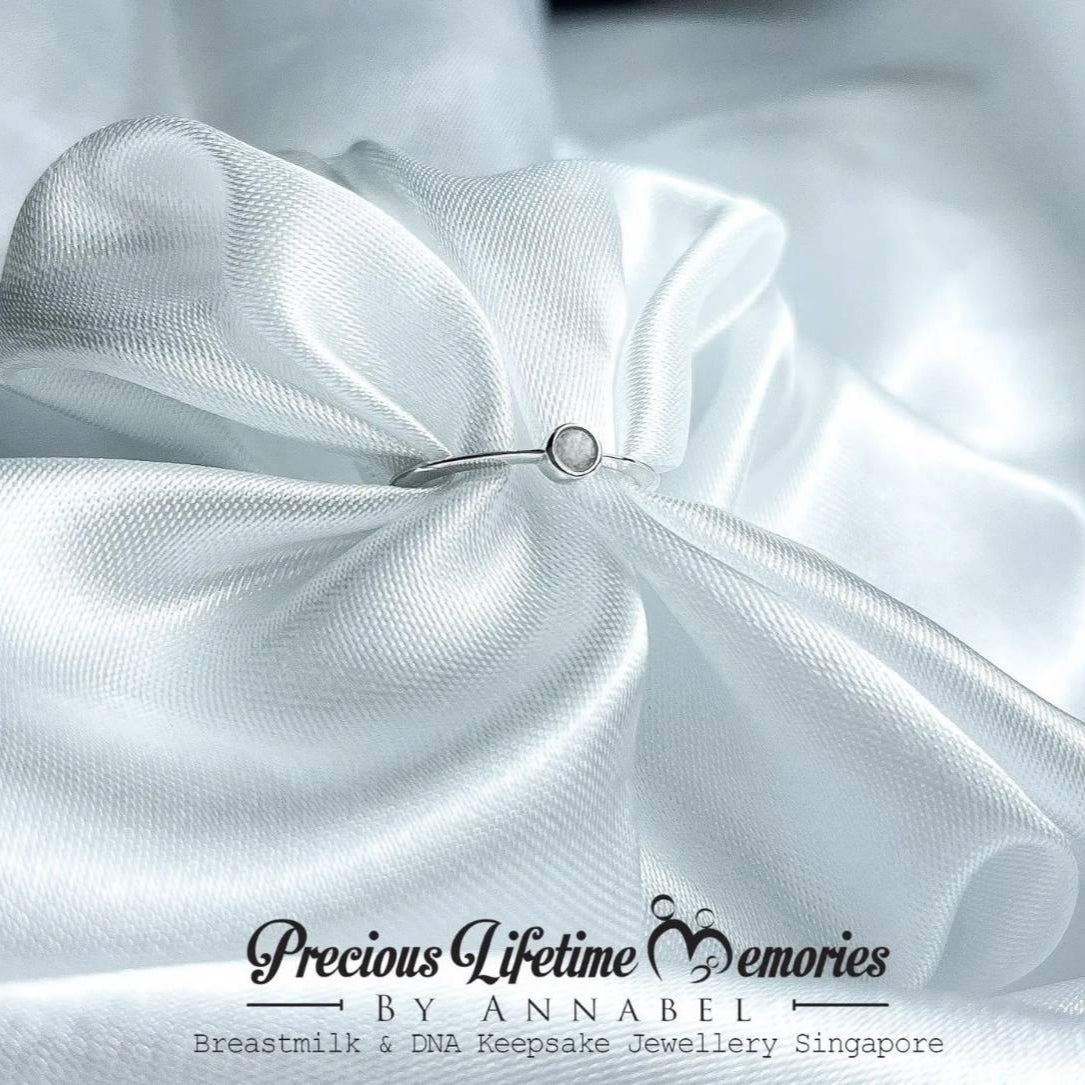 Close-up of white satin fabric with a small jewelry piece on a white background, featuring 'Precious Lifetime Memories by Annabel' branding.