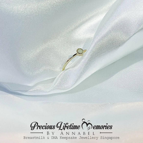 Gold ring on white fabric with 'Precious Lifetime Memories by Annabel' branding.