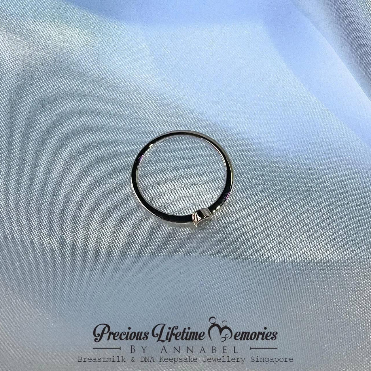 Silver ring with a small heart charm on a light blue fabric background, branded 'Precious Lifetime Memories by Annabel'.