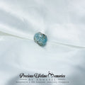 Blue gemstone charm on a white fabric background with 'Precious Lifetime Memories by Annabel' branding.