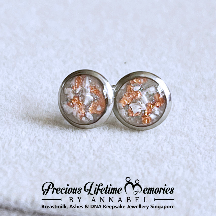 Round silver ashes earrings with embedded materials on a textured white background, branded 'Precious Lifetime Memories by Annabel'.