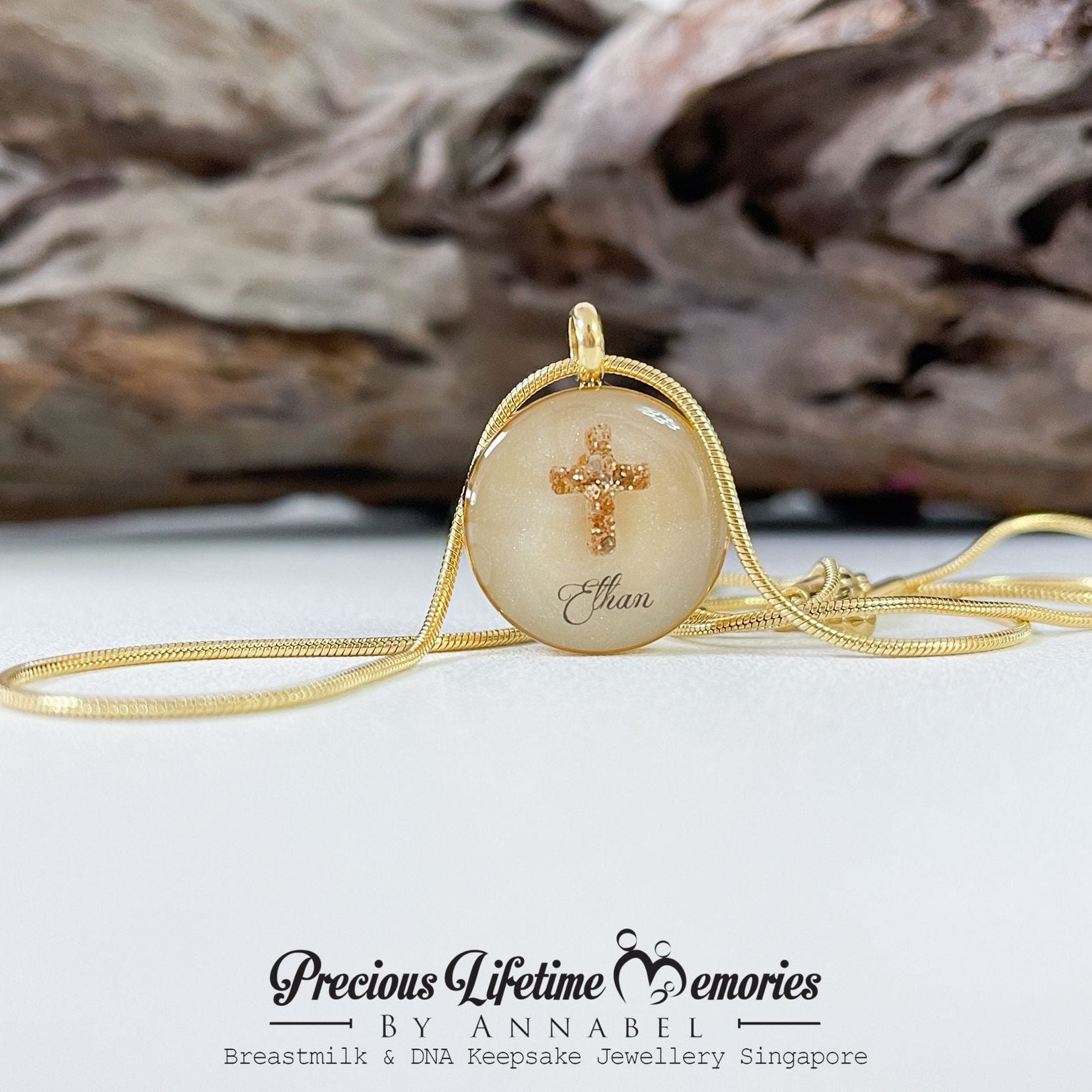 Necklace with a pendant featuring engraved text on a white surface with driftwood in the background.