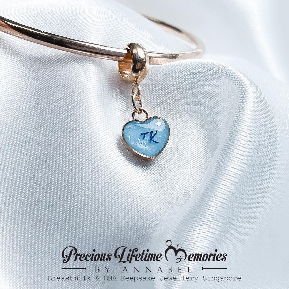 Jewelry with a blue heart charm on a white satin background, featuring 'Precious Lifetime Memories by Annabel'.