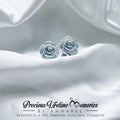 Rose-shaped earrings on white fabric with 'Precious Lifetime Memories by Annabel' branding.
