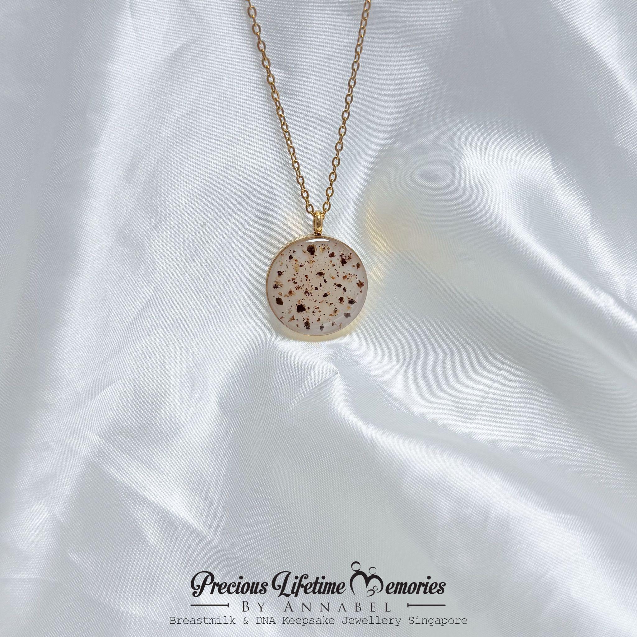 Necklace with a round, speckled pendant on a white satin background