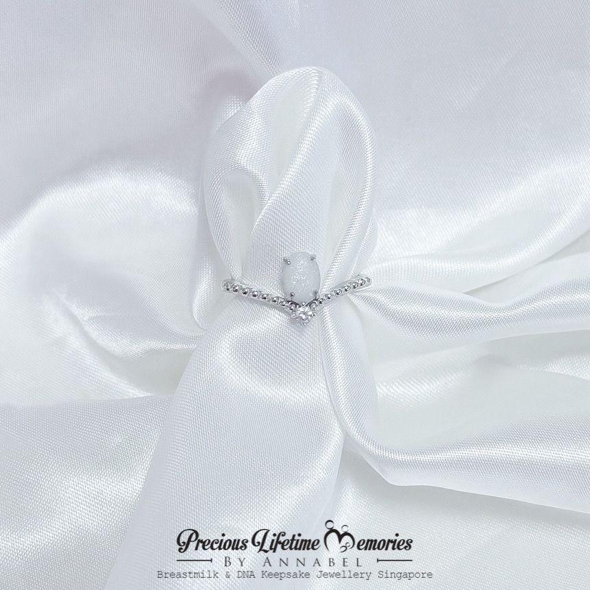 Silver ring with a white stone on a white satin fabric, branded 'Precious Lifetime Memories by Annabel'.